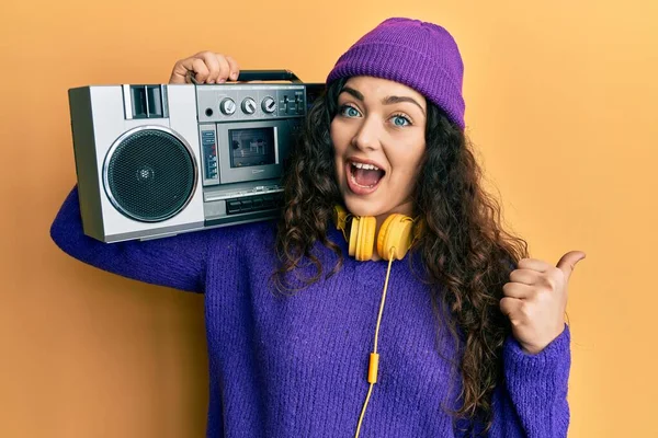 若いですブルネット女性ともに巻き毛保持Boombox 耳を傾け音楽を指す親指アップへザ側笑顔幸せとともにオープン口 — ストック写真