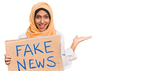 Young Brunette Arab Woman Holding Fake News Banner Celebrating Victory — Stock Photo, Image