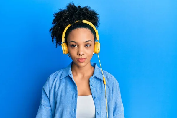 年轻的非洲裔美国女孩用耳机听音乐 脸上有严肃的表情 简单而自然地看着相机 — 图库照片