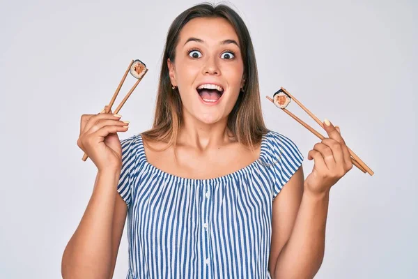 Mulher Branca Bonita Comer Sushi Usando Pauzinhos Celebrando Louco Espantado — Fotografia de Stock