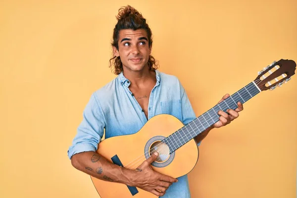 Jovem Hispânico Tocando Guitarra Clássica Sorrindo Olhando Para Lado Olhando — Fotografia de Stock