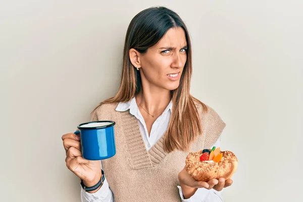 Brunetka Młoda Kobieta Pijąca Kawę Jedząca Ciasto Bez Pojęcia Zdezorientowana — Zdjęcie stockowe