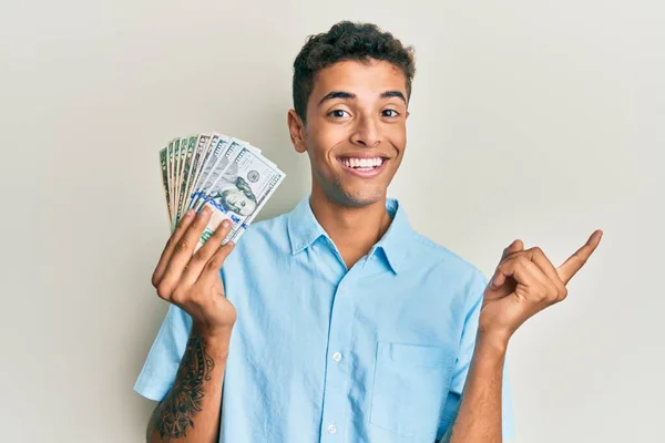 Joven Hombre Afroamericano Guapo Sosteniendo Dólares Sonriendo Feliz Señalando Con —  Fotos de Stock