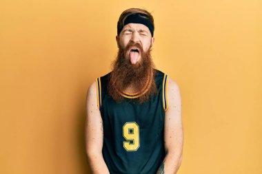 Uzun sakallı, basketbol forması giyen, komik bir ifadeyle dilini dışarı çıkaran kızıl saçlı adam. duygu kavramı. 