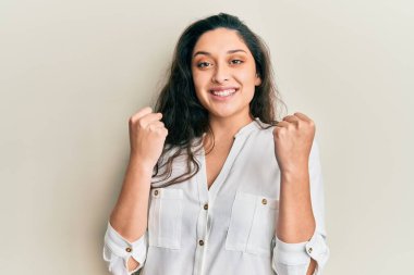 Güzel bir ortadoğulu kadın gündelik giysiler giyip kollarını kaldırarak ve açık gözlerle başarıyı kutluyor. Kazanan konsept. 