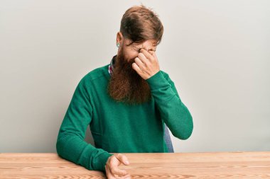 Genç İrlandalı kızıl saçlı adam, gündelik giysiler içinde masada oturuyor. Yorgun, burnu ve gözleri ovuşturuyor. Yorgunluk ve baş ağrısı hissediyor. Stres ve hüsran kavramı. 