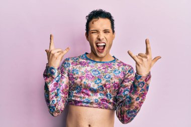 Moda kıyafetleri giymiş yakışıklı bir adam çılgın bir ifadeyle bağırıyor elleri havada rock sembolü yapıyor. Müzik yıldızı. ağır kavram. 