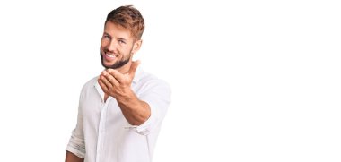 Gündelik kıyafetler giyen genç beyaz bir adam dostça gülümseyerek selamlama ve hoş geldin demek için tokalaşıyor. başarılı iş. 