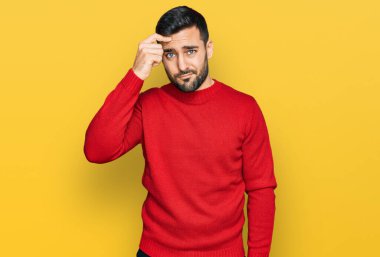 Alnındaki sivilceden mutsuz olduğunu gösteren günlük kıyafetler giyen genç İspanyol adam, siyah başlıklı çirkin enfeksiyon. sivilce ve deri problemi 