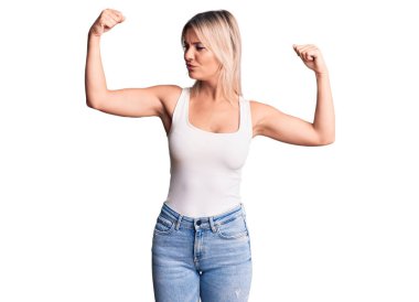 Kolsuz tişört giyen genç, güzel sarışın kadın gururla gülümseyen kol kaslarını gösteriyor. fitness konsepti. 