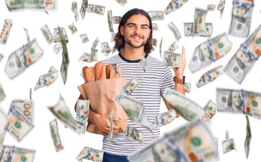 Elinde ekmek torbası olan genç yakışıklı bir adam bir fikre ya da soru işaretine şaşırmış ve mutlu bir yüzle işaret ediyor.