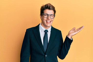 Beyaz yakalı, takım elbiseli, kravatlı, neşeli gülümseyen, eli avucunda kameraya bakan yakışıklı bir adam.. 