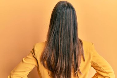 İş stili ve gözlük takan genç ve güzel bir kadın kolları vücudunda geriye doğru bakıyor. 