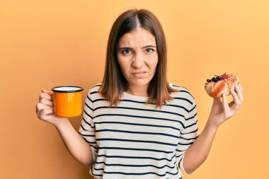 Genç, güzel bir kadın kahve içiyor, hamur işi yiyor şüpheci ve gergin, sorun yüzünden surat asıyor. negatif kişi. 