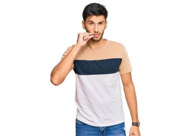 Sıradan kıyafetler giyen genç yakışıklı bir adam ağzı ve dudakları parmaklarıyla kapanan bir fermuar gibi. gizli ve sessiz, tabu konuşması 