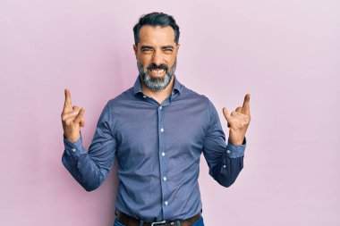 Orta yaşlı, sakallı ve gri saçlı iş kıyafetleri giyen çılgın bir ifadeyle bağıran elleri havada rock sembolü yapan bir adam. Müzik yıldızı. ağır kavram. 