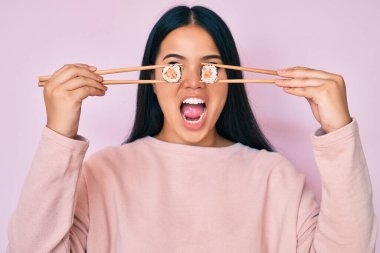 Genç, güzel Asyalı bir kız yemek çubuklarıyla gözlerine suşi sürüyor. Kızgın ve kızgın çığlıklar atıyor. Öfkeyle bağırıyor.. 