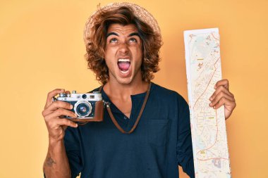 Elinde antika kamera ve şehir haritası olan genç İspanyol bir adam sinirli ve öfkeli çığlıklar atıyor öfkeyle bağırıyor, öfkeyle yukarı bakıyor. 