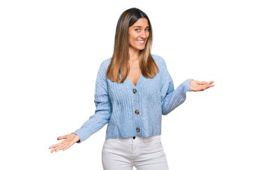 Gündelik kıyafetler giyen, neşeli gülümseyen ve kollarını açmış genç bir kadın. Hoş geldin, olumlu ve kendinden emin selamlar. 