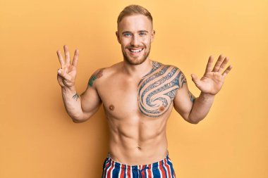 Mayo giyen genç, beyaz bir adam 8 numaralı parmaklarını gösterip gülümserken kendinden emin ve mutlu görünüyor.. 