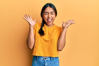 Gündelik kıyafetler giyen genç Latin kadın başarı için deli ve çılgınlığı kutluyor kollarını kaldırmış ve gözlerini kapatmış heyecanla bağırıyor. Kazanan konsept 