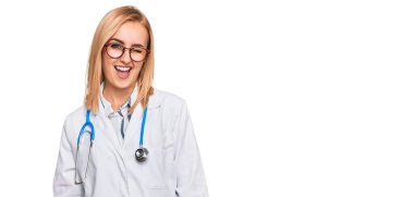 Güzel beyaz kadın doktor üniforması giyiyor ve steteskopla kameraya bakıyor. Seksi bir ifadeyle, neşeli ve mutlu bir yüzle.. 