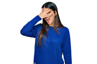 Gündelik kıyafetler giyen genç İspanyol kadın şok içinde yüzünü ve gözlerini kapayarak utanmış ifadesiyle parmaklarının arasından bakıyor.. 