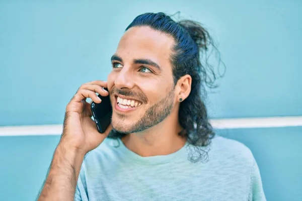 Joven Hombre Hispano Sonriendo Feliz Hablando Smartphone Apoyado Pared —  Fotos de Stock