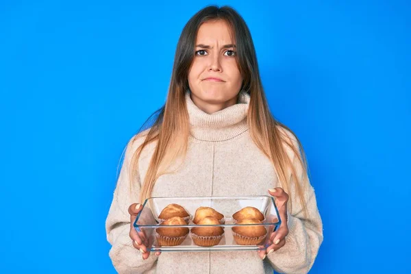 Beautiful Caucasian Woman Holding Homemade Muffins Skeptic Nervous Frowning Upset — Stock Photo, Image