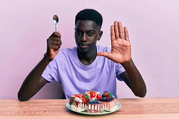 Jeune Homme Afro Américain Assis Sur Table Mangeant Des Gâteaux — Photo