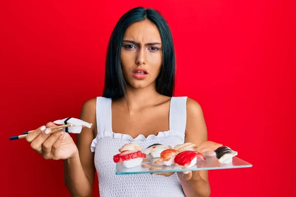 Jovem Morena Comendo Sushi Morango Usando Pauzinhos Rosto Choque Parecendo — Fotografia de Stock