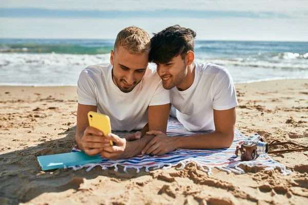 Jong Gay Paar Met Behulp Van Smartphone Liggend Het Zand — Stockfoto