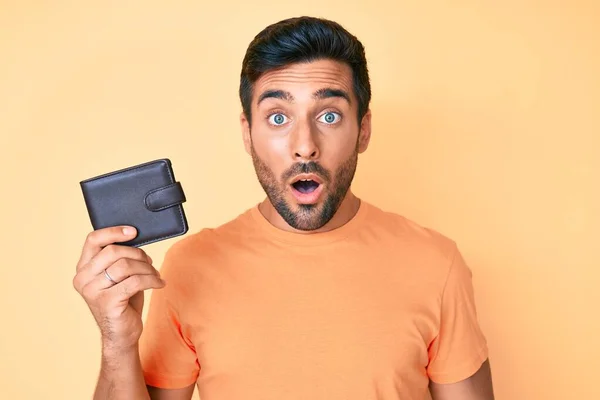 Young Hispanic Man Holding Leather Wallet Scared Amazed Open Mouth — Stock Photo, Image