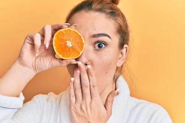 Mladá Blondýnka Županu Držící Svěží Oranžová Zakrytá Ústa Rukou Šokovaná — Stock fotografie