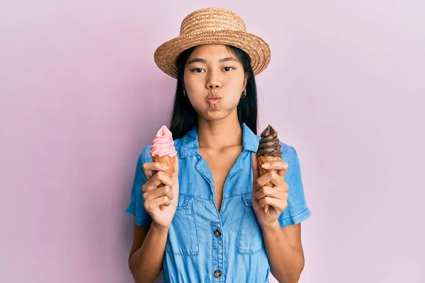 Young chinese woman wearing summer style holding ice cream puffing cheeks with funny face. mouth inflated with air, catching air.