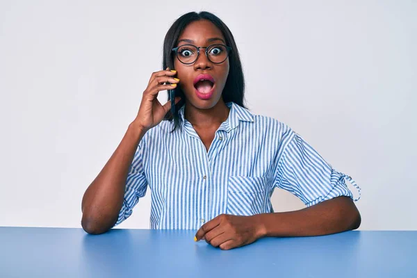 Mujer Afroamericana Joven Hablando Teléfono Inteligente Sentado Mesa Asustado Sorprendido —  Fotos de Stock