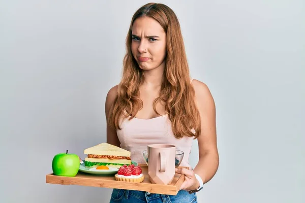 Mujer Rubia Joven Sosteniendo Bandeja Con Comida Desayuno Escéptico Nervioso — Foto de Stock