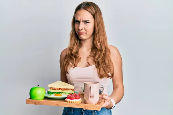 Mujer Rubia Joven Sosteniendo Bandeja Con Comida Desayuno Escéptico Nervioso —  Fotos de Stock