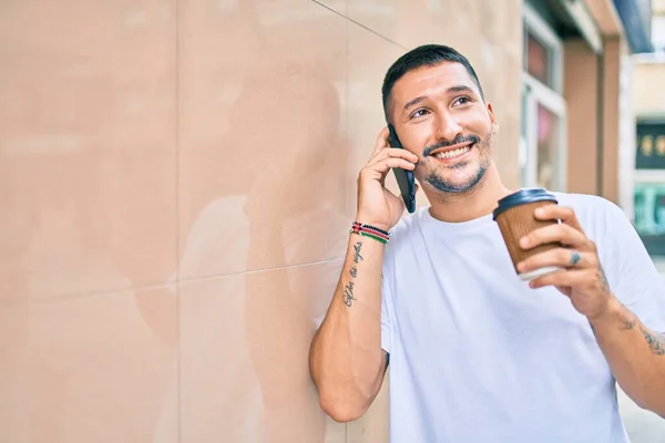 Giovane Uomo Ispanico Parlando Sullo Smartphone Bevendo Caffè Appoggiato Muro — Foto Stock