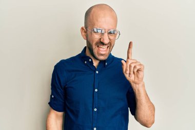 Gündelik kıyafetler giyen ve gözlüklü genç İspanyol başarılı bir fikirle işaret ediyor. Heyecanlı ve mutlu. Bir numara.. 