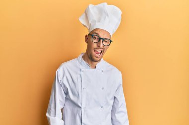 Profesyonel aşçı üniforması giyen kel bir adam kameraya seksi bir ifadeyle bakıyor, neşeli ve mutlu bir yüz.. 