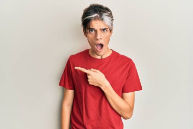 Gündelik giysiler giyen genç İspanyol adam parmaklarını yana doğru göstererek şaşırdı, ağzı açık hayret içinde kaldı.. 