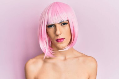 Pembe peruk takan kadın makyajı yapan genç adam yüzünde ciddi bir ifadeyle rahatlamış. Basit ve doğal bir şekilde kameraya bakıyorsun.. 