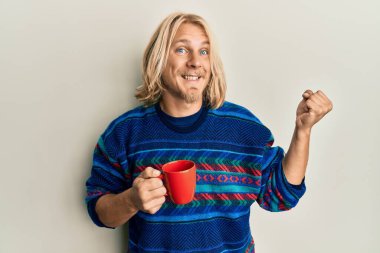 Kafkasyalı, uzun saçlı, bir fincan kahve içen gururlu, zaferi kutlayan ve kollarını kaldırarak heyecanlanan genç bir adam. 