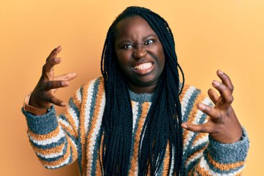 Saçları örgülü genç siyahi bir kadın öfkeyle bağırıyor, elleri boğazlamaya çalışıyor, deli gibi bağırıyor. 