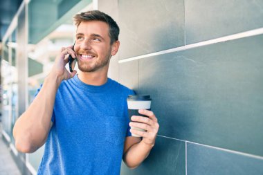 Kafkasyalı genç adam akıllı telefonla konuşuyor ve şehirde kahve içiyor..