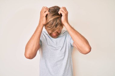 Genç, sarışın, günlük kıyafetler giyen, baş ağrısı çeken çaresiz ve stresli bir adam. Çünkü acı ve migren ağrısı var. Eller başının üstünde.. 