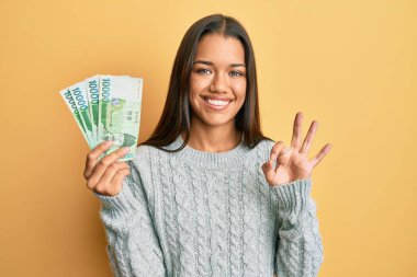 10000 Güney Koreli 'yi elinde tutan güzel İspanyol kadın banknot kazandı. Parmaklarıyla imza atıyor, gülümseyerek mükemmel bir sembol oluşturuyor. 