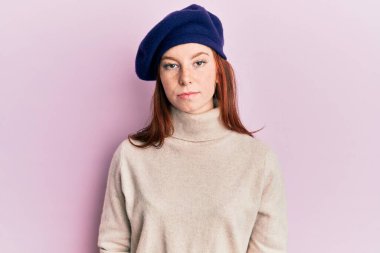 Genç, kızıl saçlı, Fransız görünümlü, bereli, yüzünde ciddi bir ifade olan bir kız. Basit ve doğal bir şekilde kameraya bakıyorsun.. 