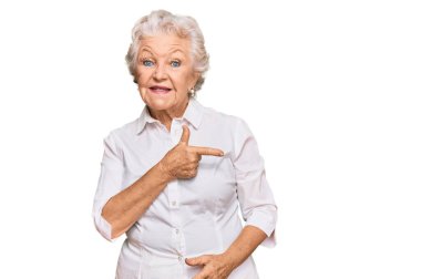 Son sınıf gri saçlı, günlük kıyafetler giyen, neşeli yüzlü, elleri ve parmaklarıyla gülümseyen mutlu ve doğal bir ifade takınan bir kadın. 